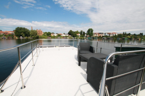 View from Houseboat «Friedrich» in Germany with outdoor seating and panoramic river and town background.