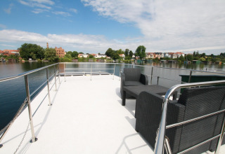 View from Houseboat «Friedrich» in Germany with outdoor seating and panoramic river and town background.