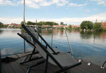 Deux chaises longues sur une terrasse de péniche avec vue sur la rivière et la ville à Houseboat Friedrich.