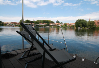 Deux chaises longues sur une terrasse de péniche avec vue sur la rivière et la ville à Houseboat Friedrich.