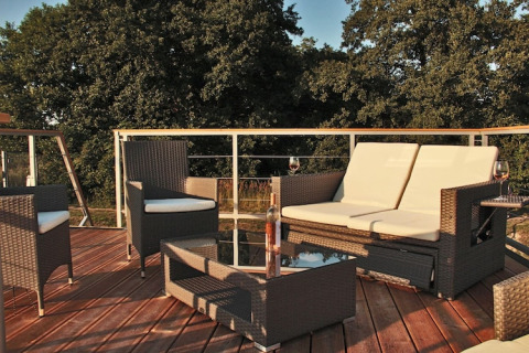 Outdoor sitting area on Houseboat «Xenia» in Germany featuring patio furniture and lush forest views.