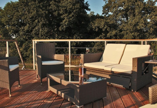Outdoor sitting area on Houseboat «Xenia» in Germany featuring patio furniture and lush forest views.