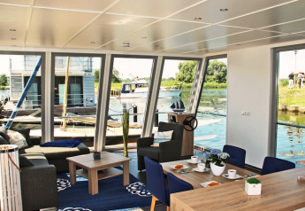 Interiørbillede af husbåden «Xenia» i Tyskland, med udsigt over vandet og lys, moderne indretning.