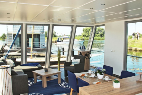 Interior of the houseboat «Xenia» in Germany, featuring water views, modern decor, and cozy seating.