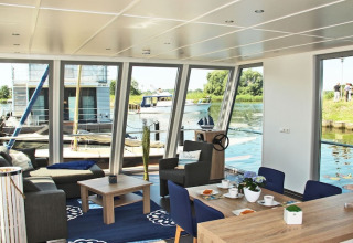 Interior of the houseboat «Xenia» in Germany, featuring water views, modern decor, and cozy seating.