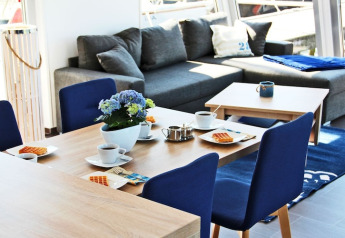 Licht, modern eetgedeelte op houseboat Xenia in Duitsland met blauwe stoelen en grijze zetel.