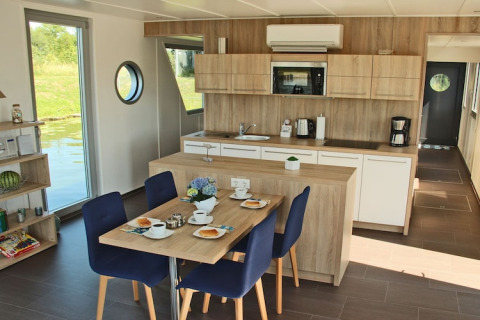 Modern kitchen and dining area on Houseboat Xenia in Germany, featuring wood decor and water views.