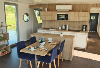 Modern kitchen and dining area on Houseboat Xenia in Germany, featuring wood decor and water views.