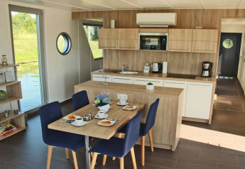 Moderne keuken en eetruimte op woonboot Xenia in Duitsland, met houten accenten en zicht op het water.