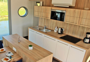 Moderne keuken op woonboot Xenia in Duitsland met houten afwerking, uitrusting en patrijspoort.