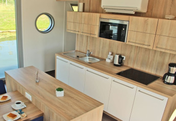 Moderne keuken op woonboot Xenia in Duitsland met houten afwerking, uitrusting en patrijspoort.