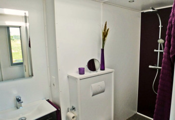 Moderne badkamer op woonboot Xenia in Duitsland met paarse accenten, douche en witte muren.