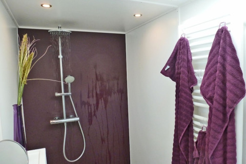 Modern shower area on Houseboat 'Xenia' in Germany with purple wall, robes, and contemporary fixtures.
