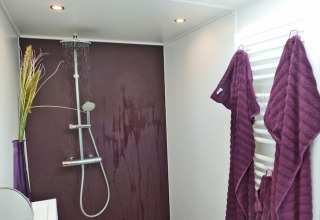 Modern shower area on Houseboat 'Xenia' in Germany with purple wall, robes, and contemporary fixtures.