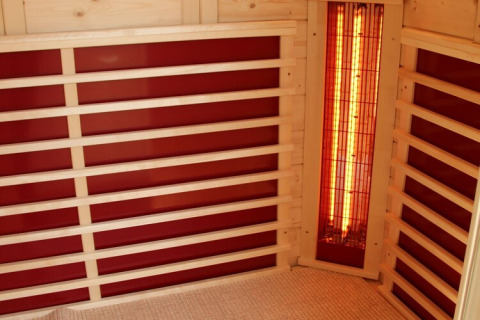 Interior of an infrared sauna on Houseboat ‘Xenia’ in Germany, featuring wood benches and red panels.