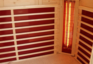 Interior of an infrared sauna on Houseboat ‘Xenia’ in Germany, featuring wood benches and red panels.