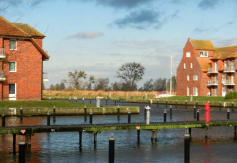 Zicht vanaf woonboot Xenia in Duitsland, met kanalen, bakstenen gebouwen en een zeilboot verderop.