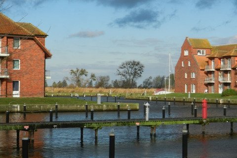 View from houseboat Xenia in Germany, showing canals, brick buildings, and a sailboat in the distance.