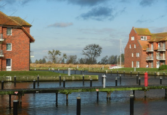 Zicht vanaf woonboot Xenia in Duitsland, met kanalen, bakstenen gebouwen en een zeilboot verderop.