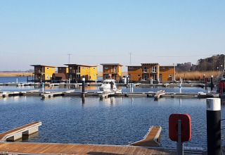 Foto van moderne woonboten in een jachthaven met houten steigers en rustig water op een zonnige dag.