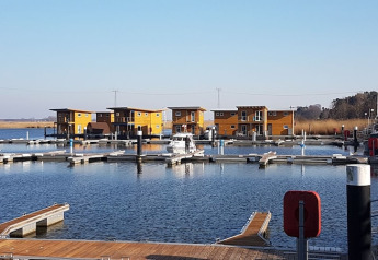 Foto de modernas casas flotantes atracadas en un puerto deportivo con muelles de madera y agua tranquila.