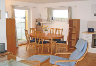 Houseboat interior with dining table, six wooden chairs, cozy seating, and large windows above the water.