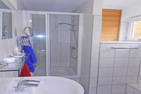 Baño moderno en una casa flotante con ducha, lavabo, ventana con persiana y barra para toallas.
