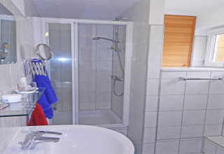 Modern houseboat bathroom with shower, sink, window with blind, towel rack and essential toiletries.
