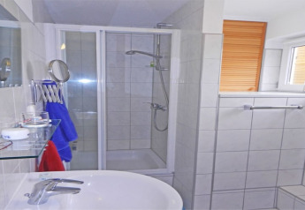 Modern houseboat bathroom with shower, sink, window with blind, towel rack and essential toiletries.