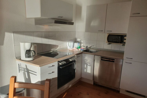 Modern houseboat kitchen with coffee maker, stove, oven, sink, microwave, and dishwasher in sunlight.