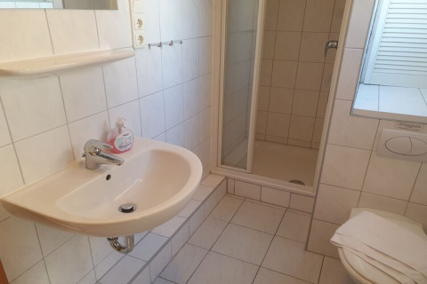 Bagno di una casa galleggiante con lavandino, doccia, WC e piastrelle chiare dallo stile moderno.