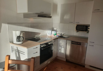 Piccola cucina moderna su una houseboat con lavastoviglie, forno, macchina da caffè e mobili bianchi.