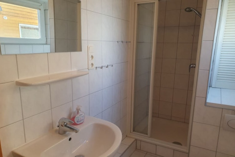 Moderne badeværelse på husbåd med bruser, håndvask, spejl og vindue i «Haus 2 - Steg F» i Tyskland.