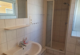 Bagno moderno su una casa galleggiante con doccia, lavabo, specchio e finestra in Germania.