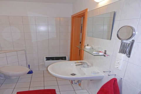 Moderne badkamer op een woonboot met wastafel, spiegel, toilet en rode handdoeken in Duitsland.
