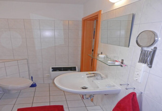 Moderne badkamer op een woonboot met wastafel, spiegel, toilet en rode handdoeken in Duitsland.