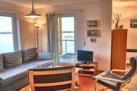 Salon sur une péniche avec canapé, fauteuils, TV et vue sur l'eau à Haus 5 - Steg F, Allemagne.