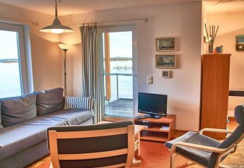Stue på husbåd med sofa, stole, tv og udsigt over vandet ved Haus 5 - Steg F, Tyskland.