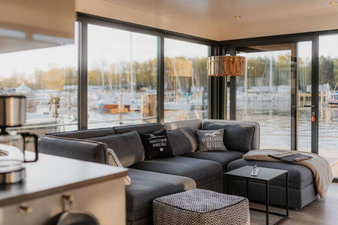 Moderne woonkamer op houseboat 475077 in Duitsland met grijze bank en uitzicht op de jachthaven.