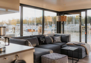 Moderne woonkamer op houseboat 475077 in Duitsland met grijze bank en uitzicht op de jachthaven.