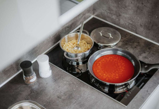 Keuken op een woonboot met een pan pasta en een koekenpan tomatensaus op het fornuis in Duitsland.