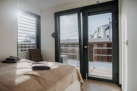 Slaapkamer met glazen deuren en raam op een woonboot in Duitsland, moderne inrichting en terras.