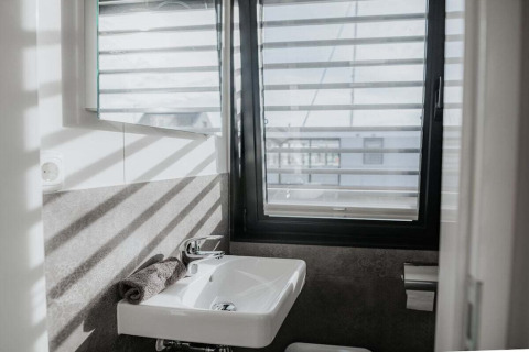 Lichte, moderne badkamer op woonboot '475077' in Duitsland met raam, wastafel, handdoek en wc-papier.