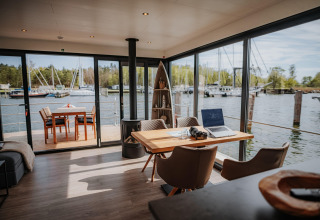 Moderne interiør på husbåd i Peenemünde med udsigt til havn, terrassebord og bærbar computer.
