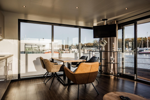 Sala de estar luminosa en una casa flotante en Peenemünde con muebles modernos y vista al puerto.