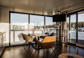 Lichte leefruimte op een woonboot in Peenemünde met modern meubilair en uitzicht op de haven.