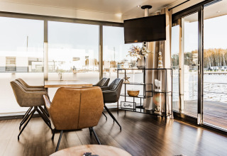 Indvendigt billede af Houseboat 'in Peenemünde' i Tyskland med moderne spisebord og store vinduer.