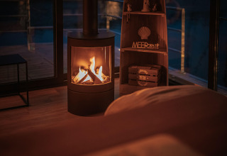 Cozy living space on a houseboat in Peenemünde with a lit fireplace and evening view of the deck.