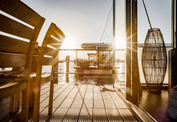 Sonnenuntergang auf dem Hausboot in Peenemünde mit Blick übers Wasser und stilvoller Holzterrasse.