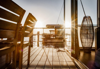 Atardecer visto desde Houseboat en Peenemünde, con terraza de madera y decoración moderna junto al agua.